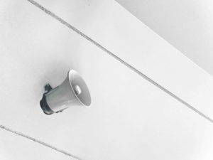 A loud speakerphone hung on a white wall.
