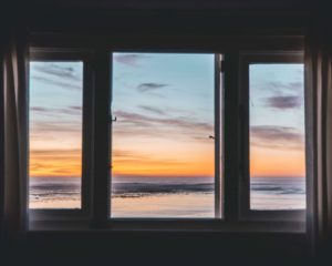 Windows looking out on a picturesque beach sunset setting